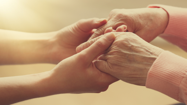 A continuing care provider holding hands with a senior